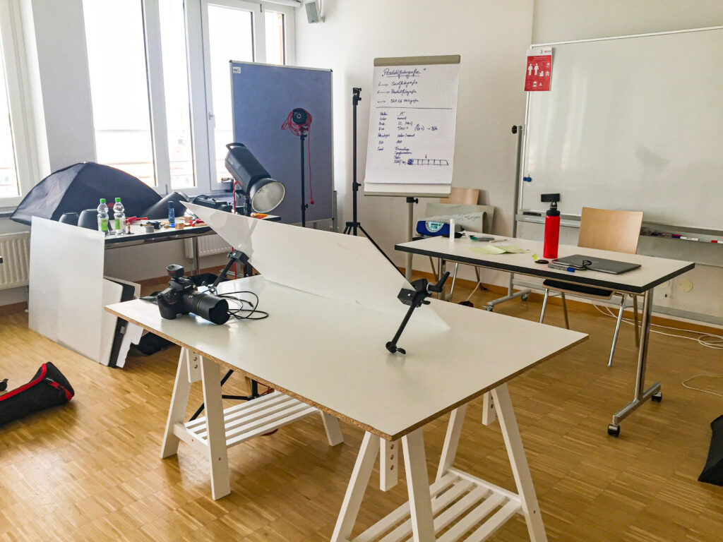 Das Foto zeigt einen Raum, in dem ich meine Fotokurse in München veranstalte. Im Kurs verwenden wir eine digitale Spiegelreflexkamera, Studiolampen und einen Aufnahmetisch.